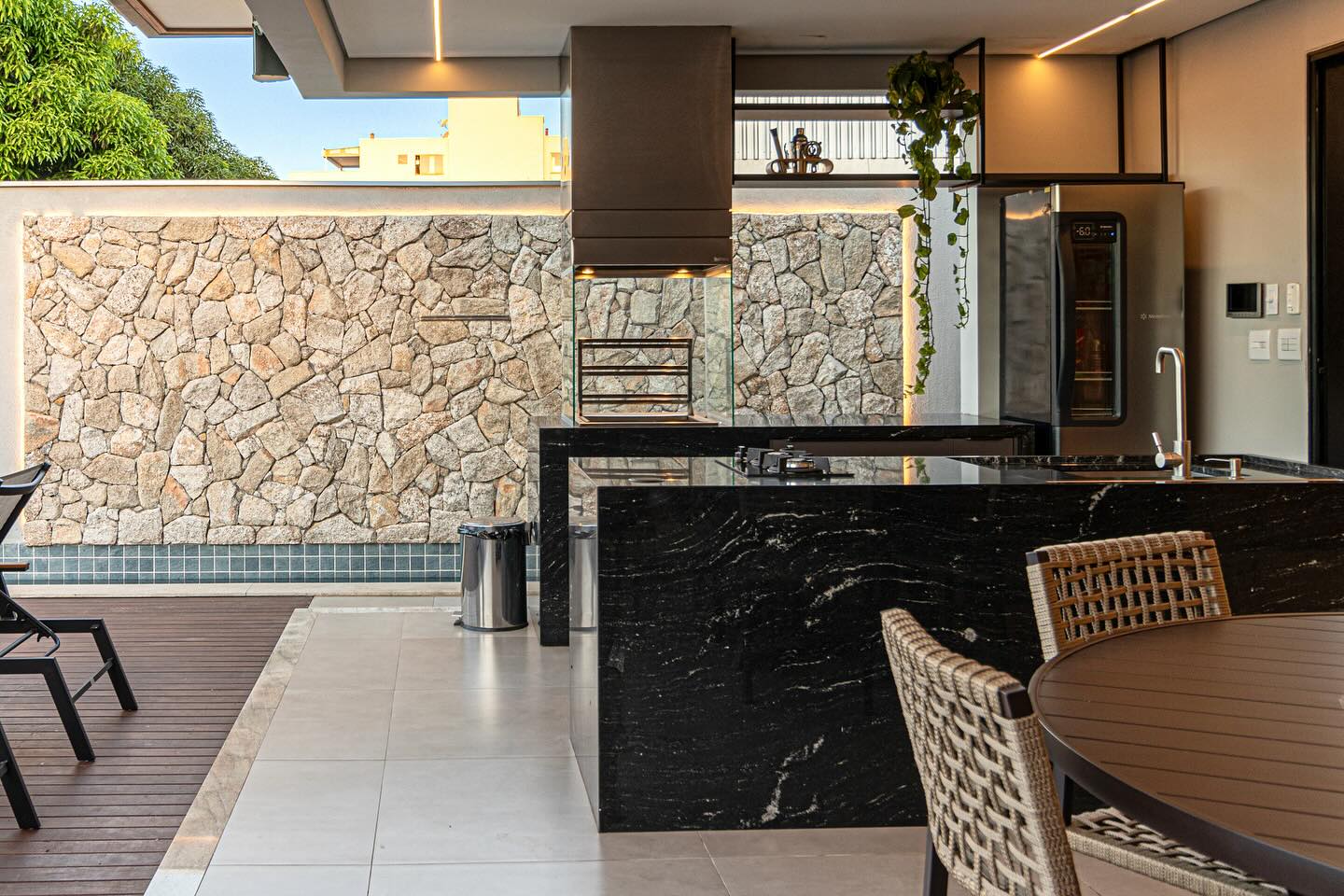 Área gourmet externa com bancada em pedra escura