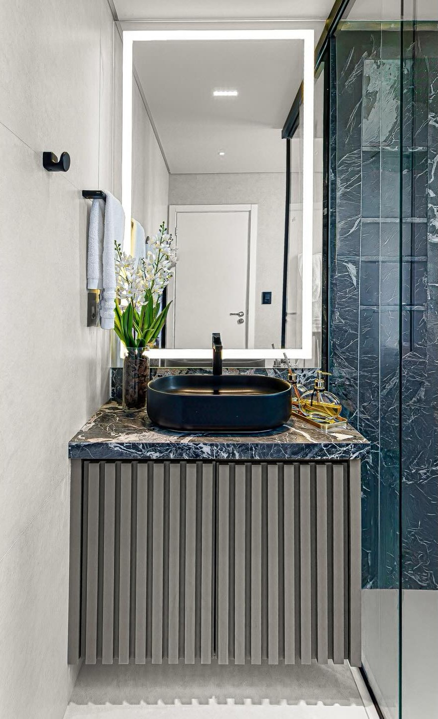 Lavabo com bancada de pedra escura e cuba de apoio
