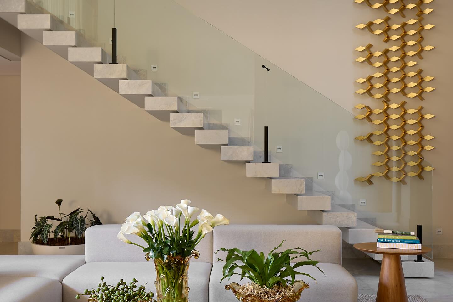 Sala de estar com escada e painel decorativo em pedra