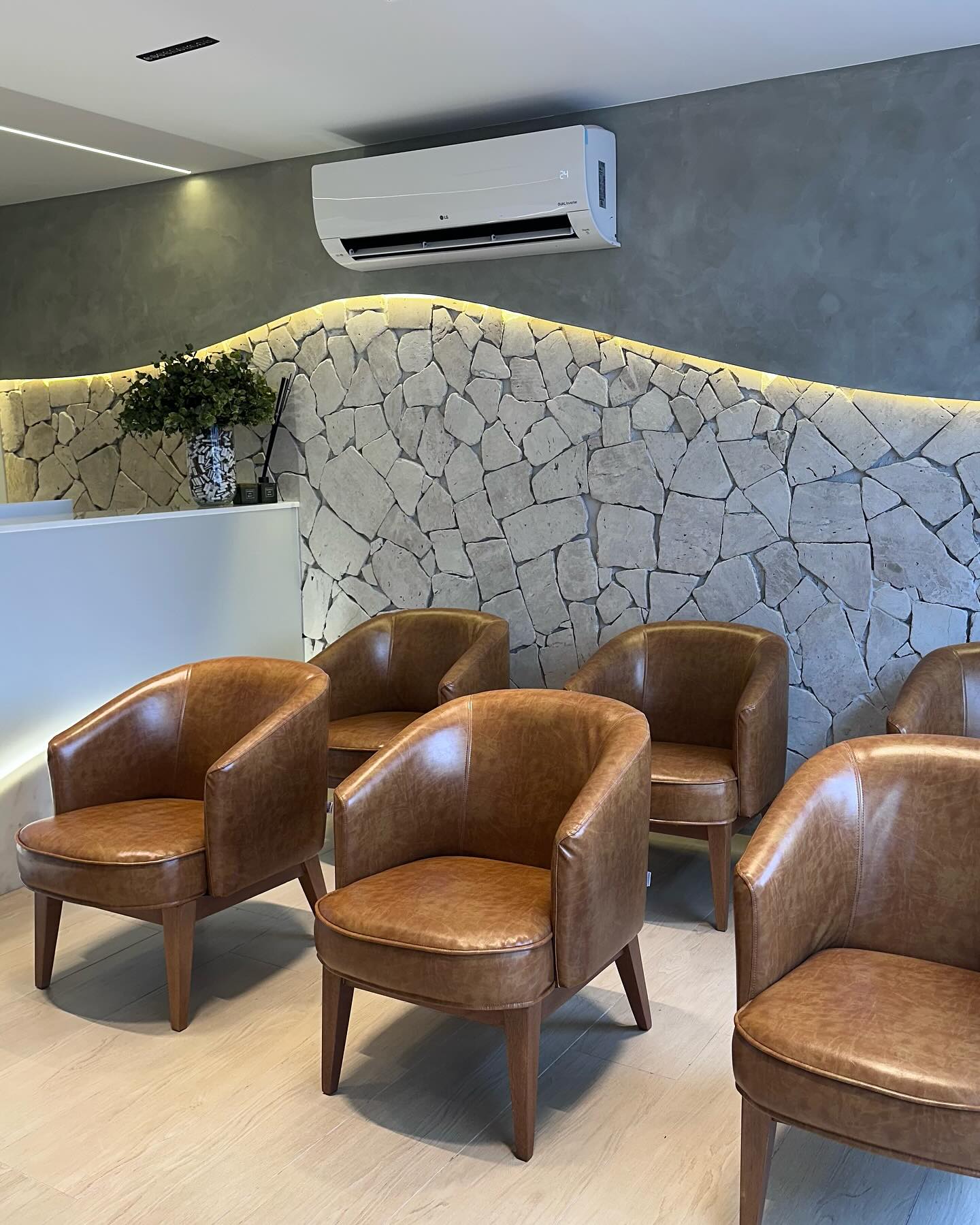 Parede em pedra natural com iluminação embutida na sala de espera de uma clínica